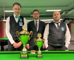 The finalists stand either side of the referee and in front of the trophies which are on the table.