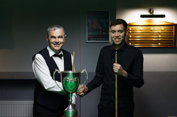 Elfed Evans and Alfie Davies shake hands by the table either side of the Welsh Championship trophy.