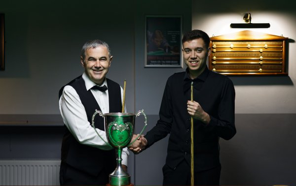 Elfed Evans and Alfie Davies shake hands by the table either side of the Welsh Championship trophy.