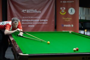 Peter Gilchrist plays a shot with the rest.