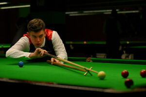 Liam Davies plays a shot with the rest.