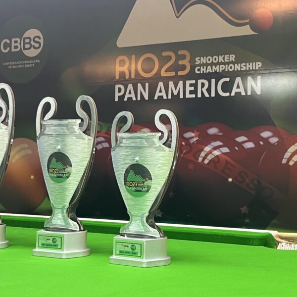 The 2023 Pan American Snooker Championship trophies are lined up on the table in front of the a big tournament wall poster.